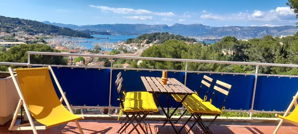 2 stoelen en een houten tafel op een balkon bij Saint Mandrier 4 pièces vue exceptionnelle - Location à la semaine uniquement in Saint-Mandrier-sur-Mer