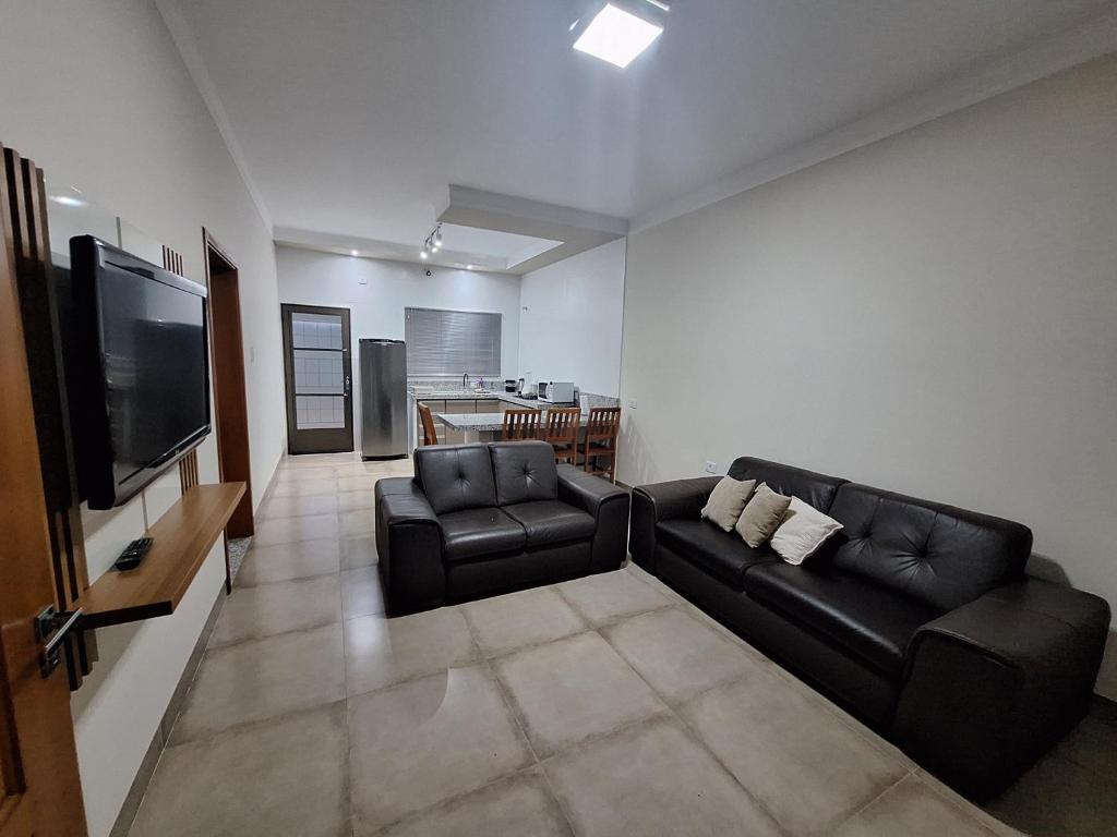 a living room with two leather couches and a flat screen tv at Regente Feijó Centro in Regente Feijó