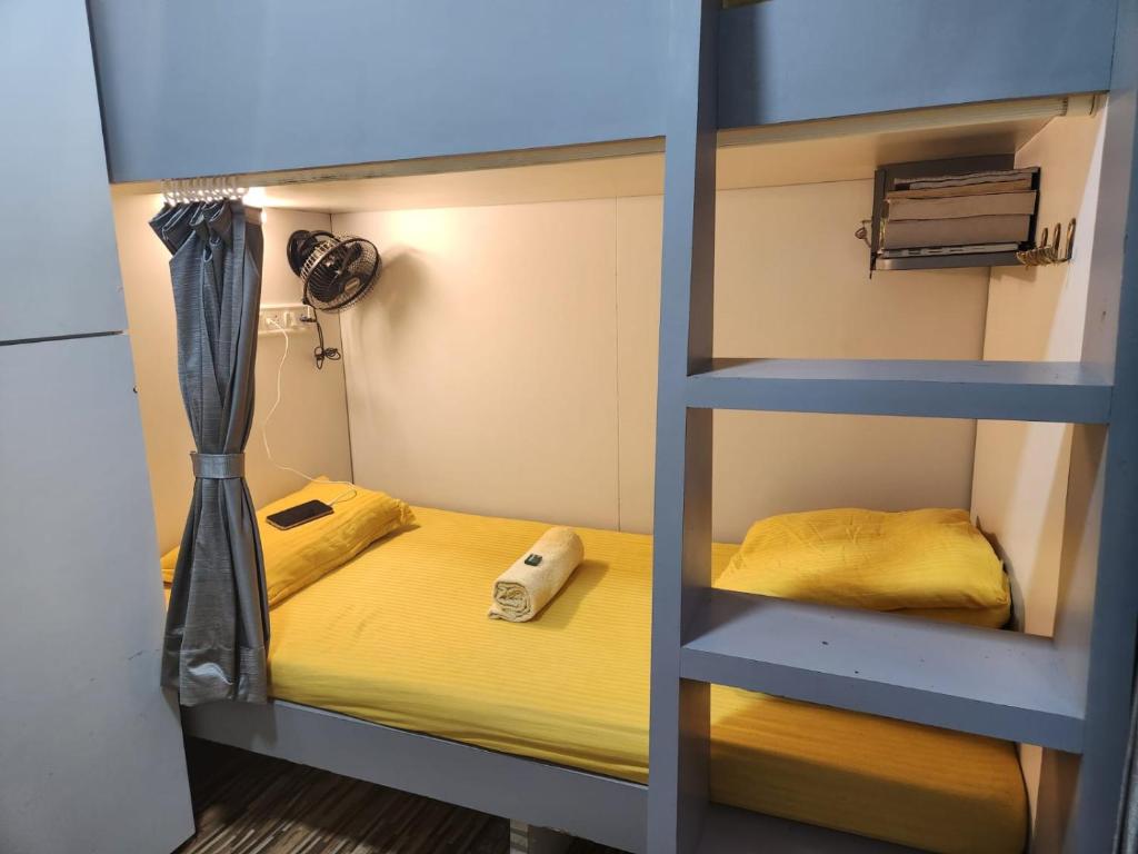 Łóżko piętrowe w pokoju z żółtym łóżkiem w obiekcie Sinhassan dormitory hostel Juhu w Bombaju