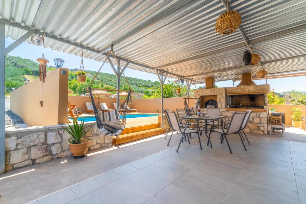 um pátio com uma mesa e cadeiras e uma piscina em Countryhouse Villa with pool & private parking em Heraclião