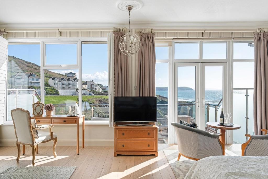 a bedroom with a bed and a tv and a desk at Watersmeet Hotel in Woolacombe