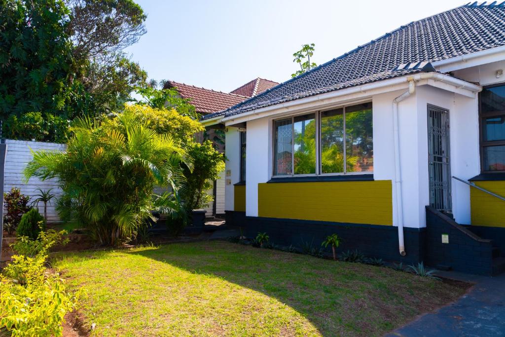 uma casa amarela e branca com um quintal em Inkanyezi Guest house em Durban
