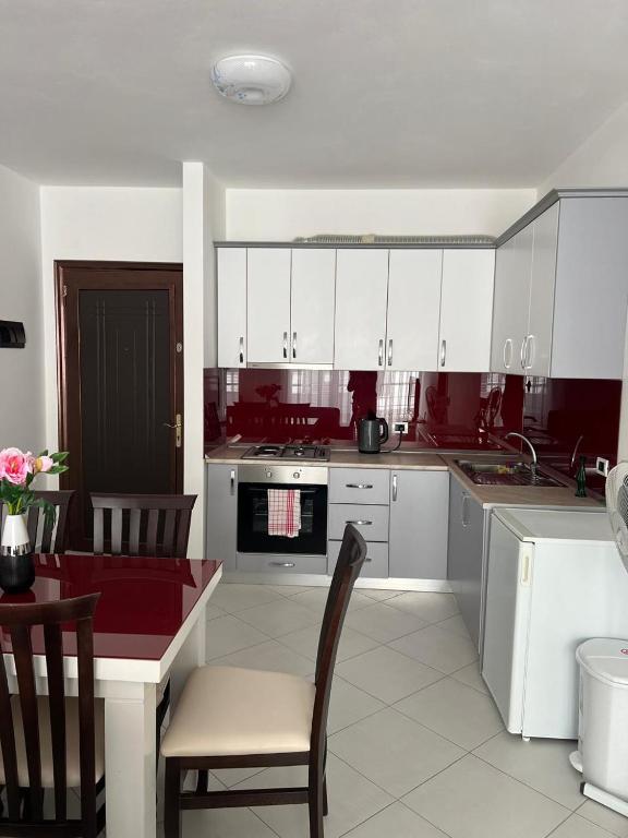 a kitchen with white cabinets and a table and chairs at Arber apartments Zeqiraj in Shëngjin
