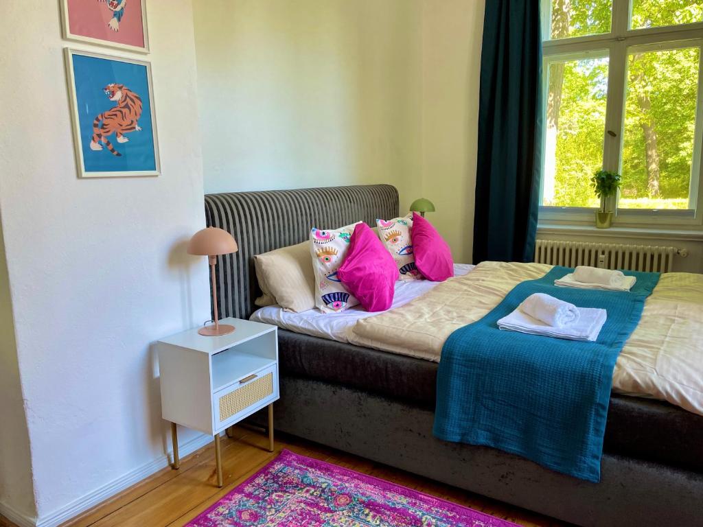 Un dormitorio con una cama con almohadas rosas y una ventana en Villa Ambiente Falkensee en Falkensee