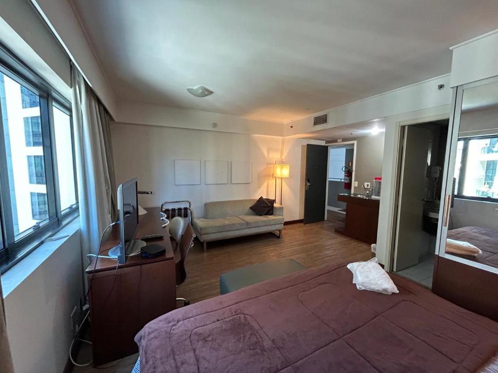 a bedroom with a bed and a living room at Apartamento em Hotel 4 estrelas - Moema in Sao Paulo
