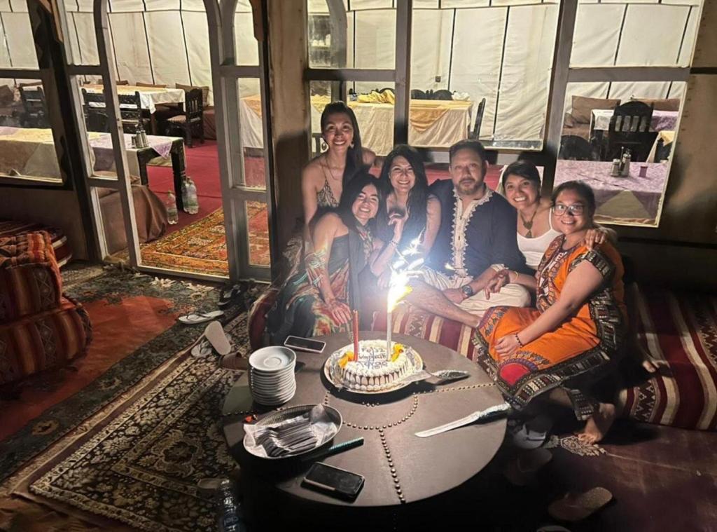 a group of people sitting around a table with a birthday cake at Sahara Luxury Camp & Camel Trek in Merzouga