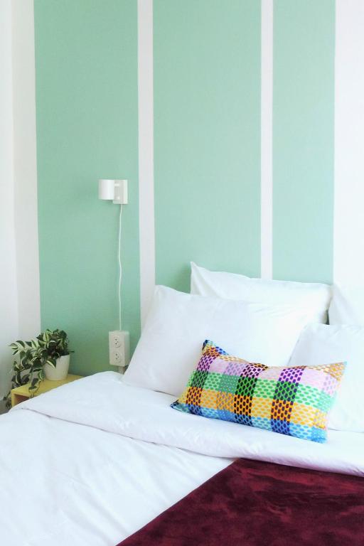 Hotel Strasbourg Evasion Pop, a white bed with a colorful pillow on it at Strasbourg Evasion Pop in Strasbourg