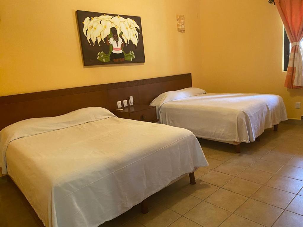une chambre d'hôtel avec 2 lits et un tableau mural dans l'établissement Marina Park Plaza, à Santa Cruz Huatulco