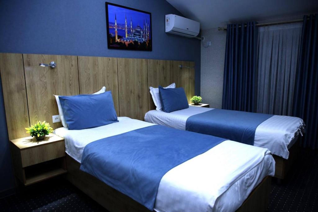 タシュケントにあるApple Hotel 小苹果酒店 FREE Airport Serviceのベッド2台、壁掛けテレビが備わるホテルルームです。