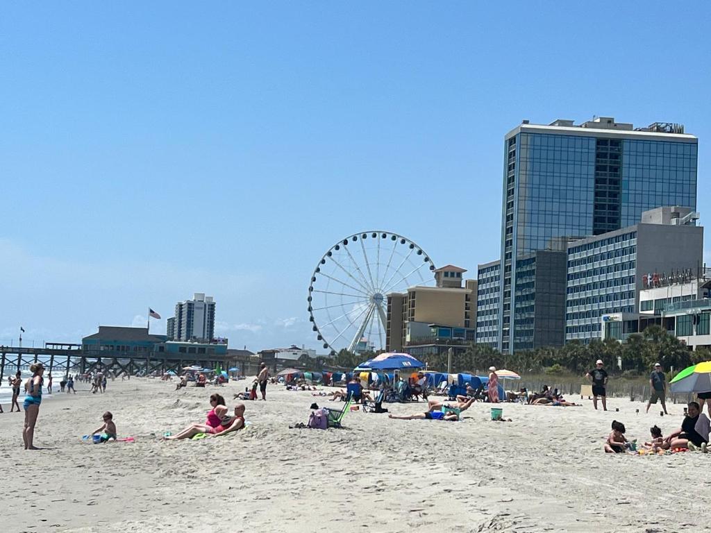 eine Gruppe von Menschen am Strand mit einem Riesenrad in der Unterkunft Oceanfront Luxury 2BR King Suite Atlantica Resort in Myrtle Beach