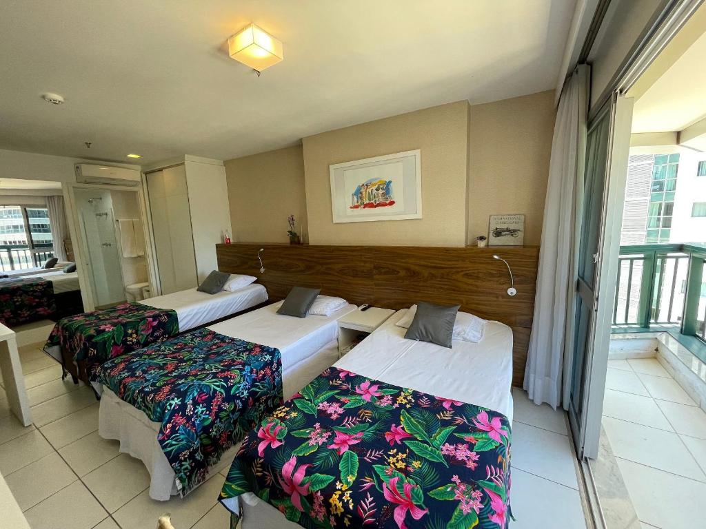 um quarto de hotel com três camas e uma varanda em V1114 Flat com WI-FI exclusivo, academia e piscinas em Brasília