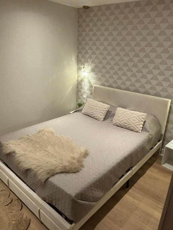 uma cama com um cobertor branco num quarto em 24 heures du Mans em Arnage