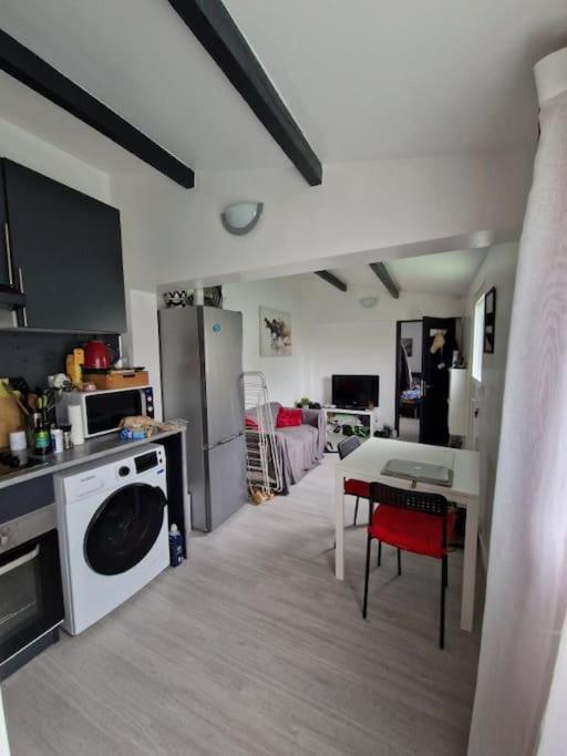 une cuisine avec une machine à laver et une table dans l'établissement charmante maisonnette, à Mitry-Mory