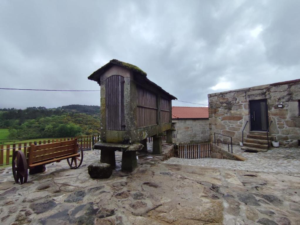 un pequeño edificio y un banco junto a un edificio en Casa do Canastro en Mondim de Basto