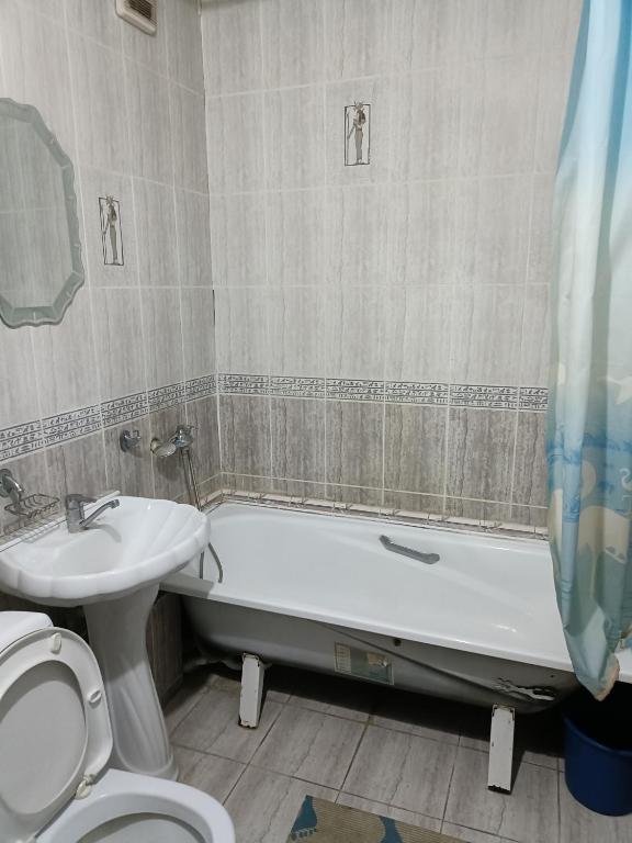 een badkamer met een wastafel, een bad en een toilet bij Квартира in Taraz