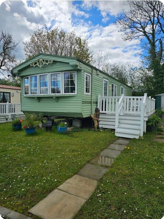 a green tiny house with a white fence at PB6 in Bettws-Evan