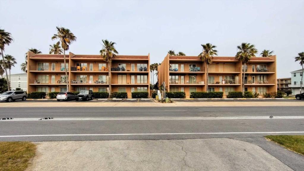 un bâtiment avec des palmiers en face d'une rue dans l'établissement Beachview 105 Condominium Condo, à South Padre Island