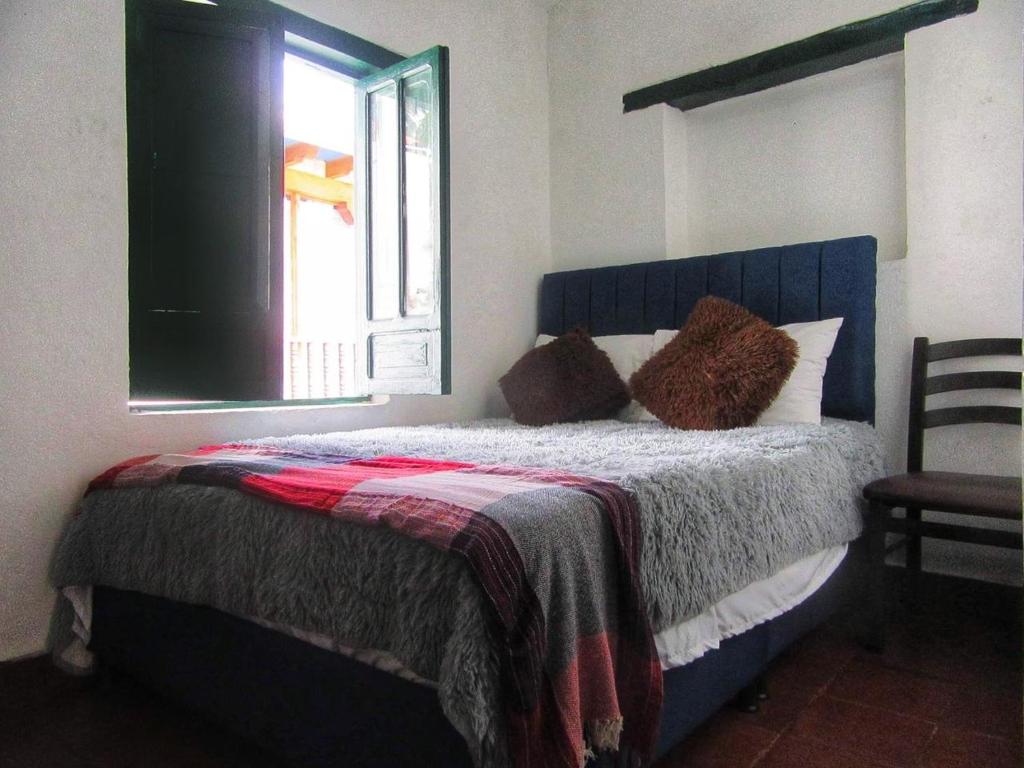 um quarto com uma cama com um cobertor e uma janela em Carazo chef Host & Food em Villa de Leyva