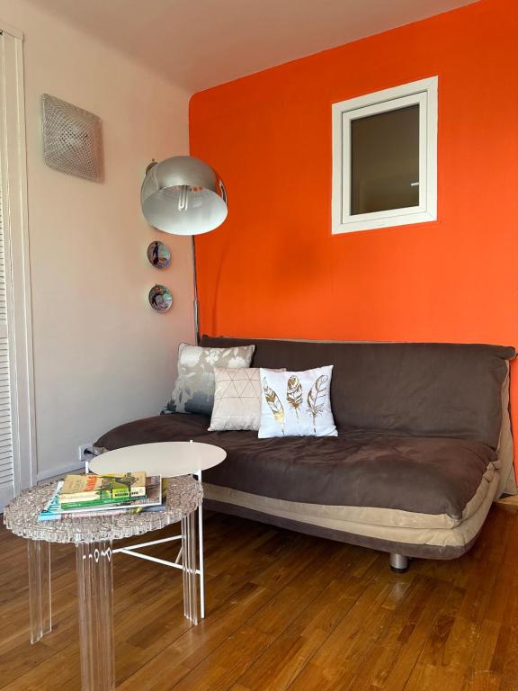 カンヌにあるStudio à deux pas de la Croisetteのリビングルーム(オレンジ色の壁のソファ付)