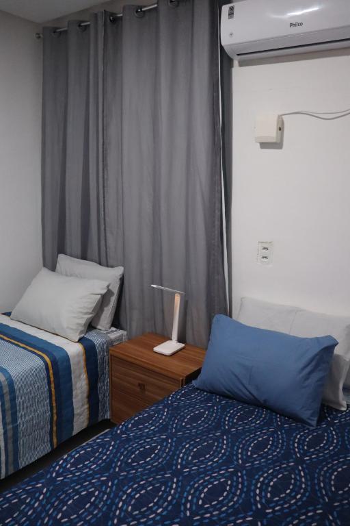 1 dormitorio con 2 camas y mesa con lámpara en Studio Casa Amarela - a 400m do Corredor Cultural, en Mossoró