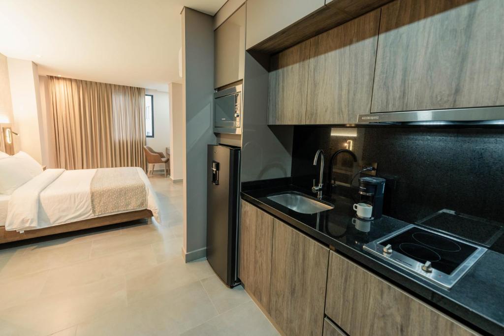 een keuken met een wastafel en een bed in een kamer bij Amari Living Suites in Barranquilla