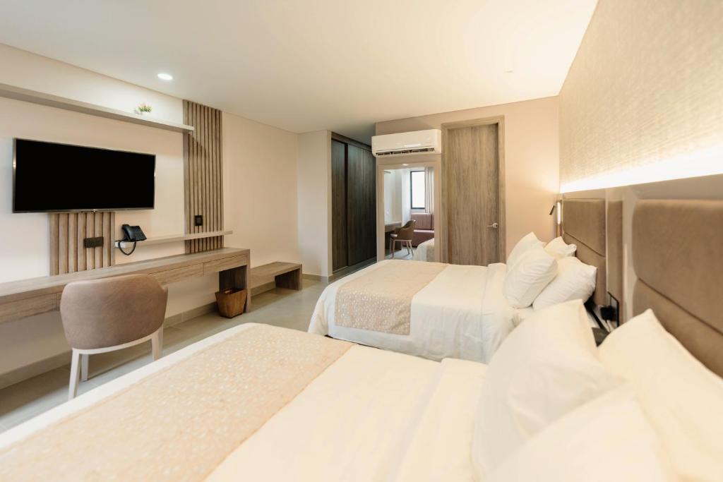 a hotel room with two beds and a flat screen tv at Amari Living Suites in Barranquilla