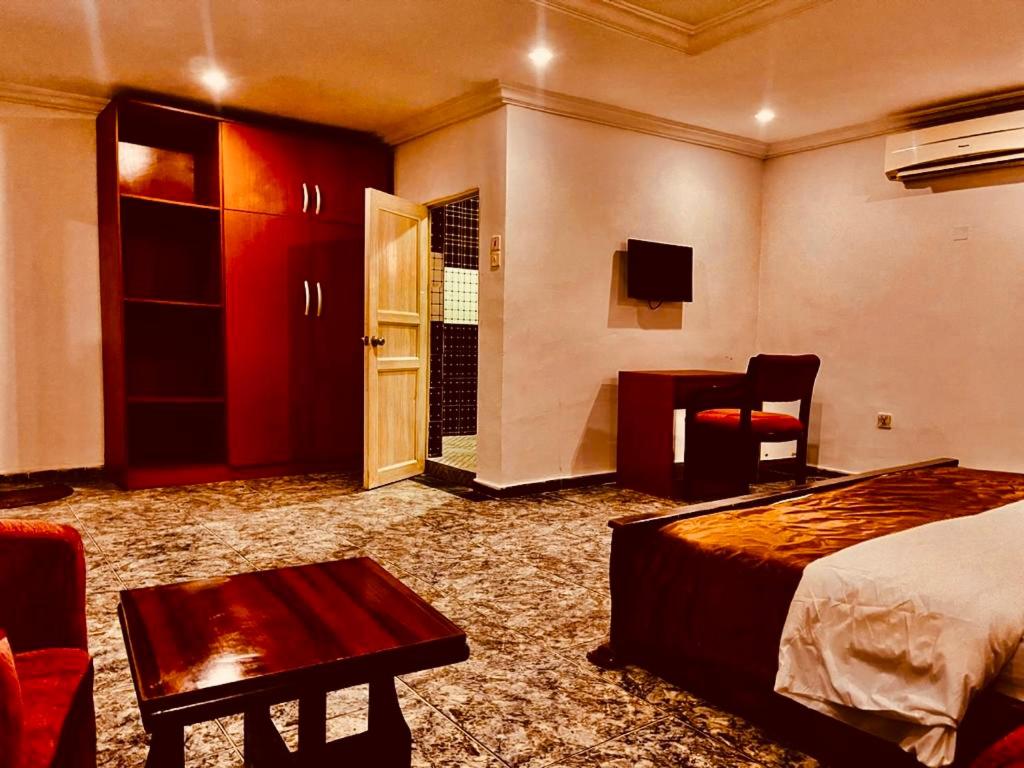 a hotel room with a bed and a desk and a chair at Executive Gold Hotel in Abuja