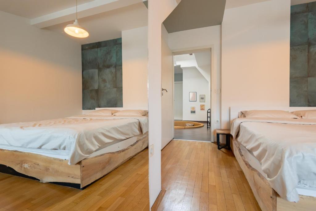 2 łóżka w pokoju z białymi ścianami i drewnianą podłogą w obiekcie Apartment 2 w Prisztinie