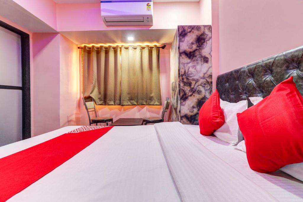 - une chambre avec un grand lit blanc et des oreillers rouges dans l'établissement OYO Flagship Kirtiraj Lodging and Boarding, à Mumbai