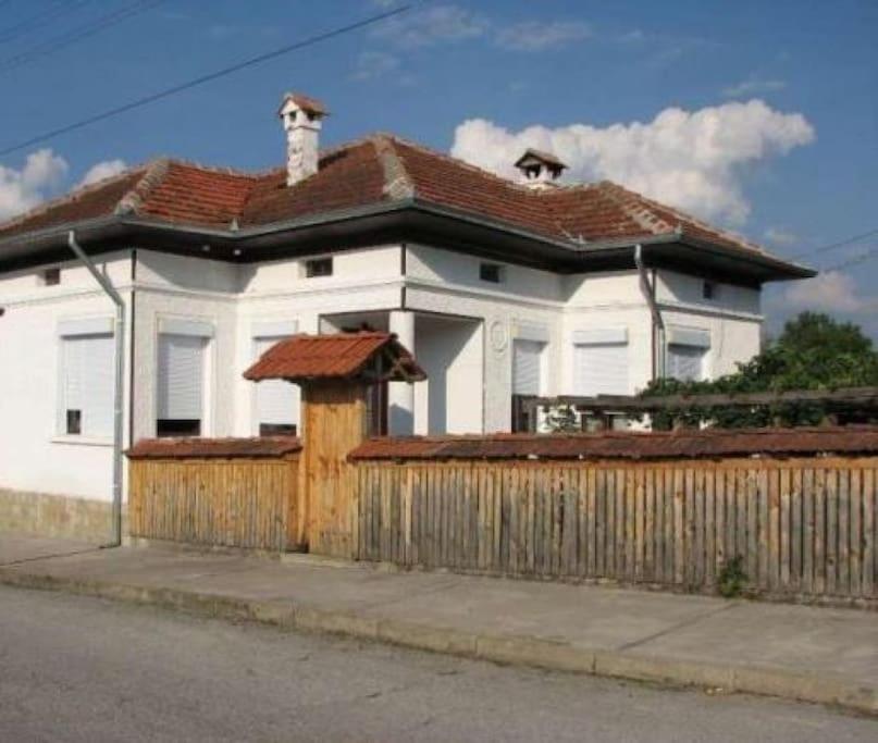Biały dom z drewnianym płotem przed nim w obiekcie Granpa house w mieście Ruhovtsi