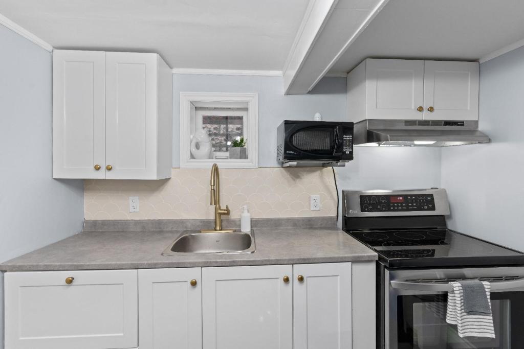 a kitchen with white cabinets and a sink at 2 Bedroom with Laundry and Parking in Windsor in Windsor