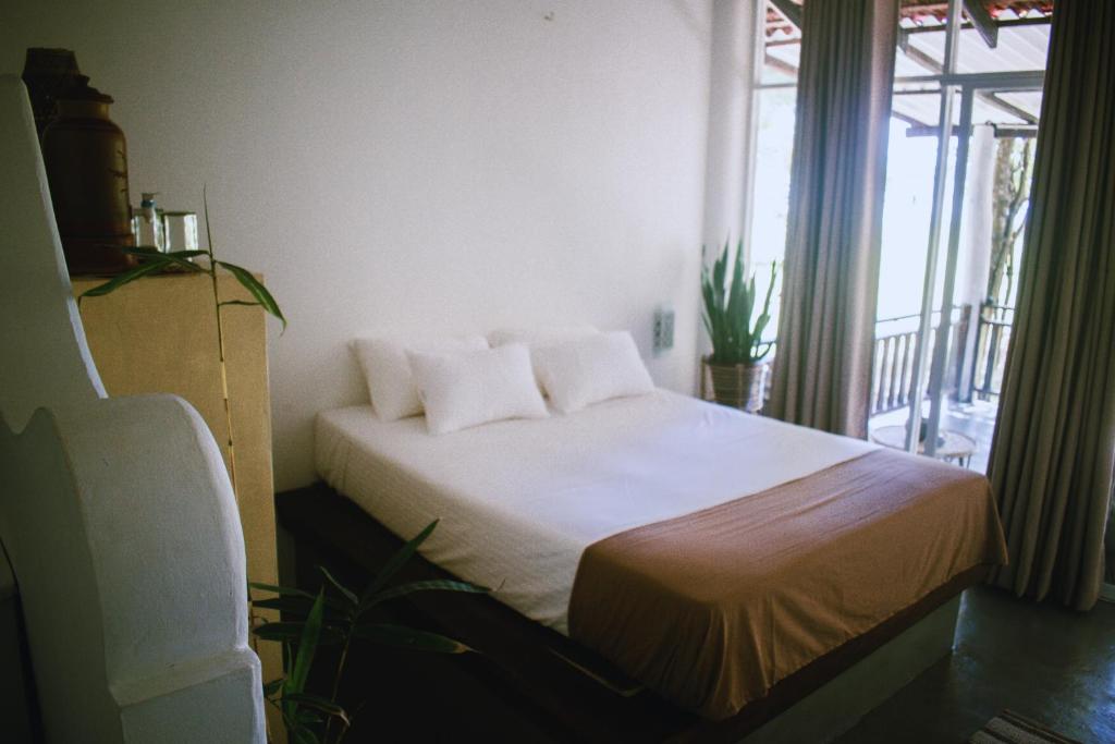 a bedroom with a bed with white sheets and a window at Calma - Surf, Yoga & Coffee on a Private Beach in Dickwella