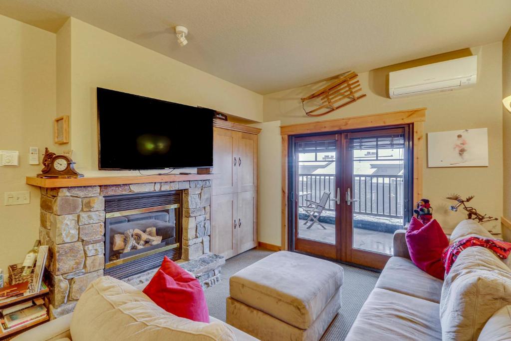 sala de estar con chimenea y TV de pantalla plana en Ski-InandSki-Out Whitefish Escape with Balcony! en Whitefish