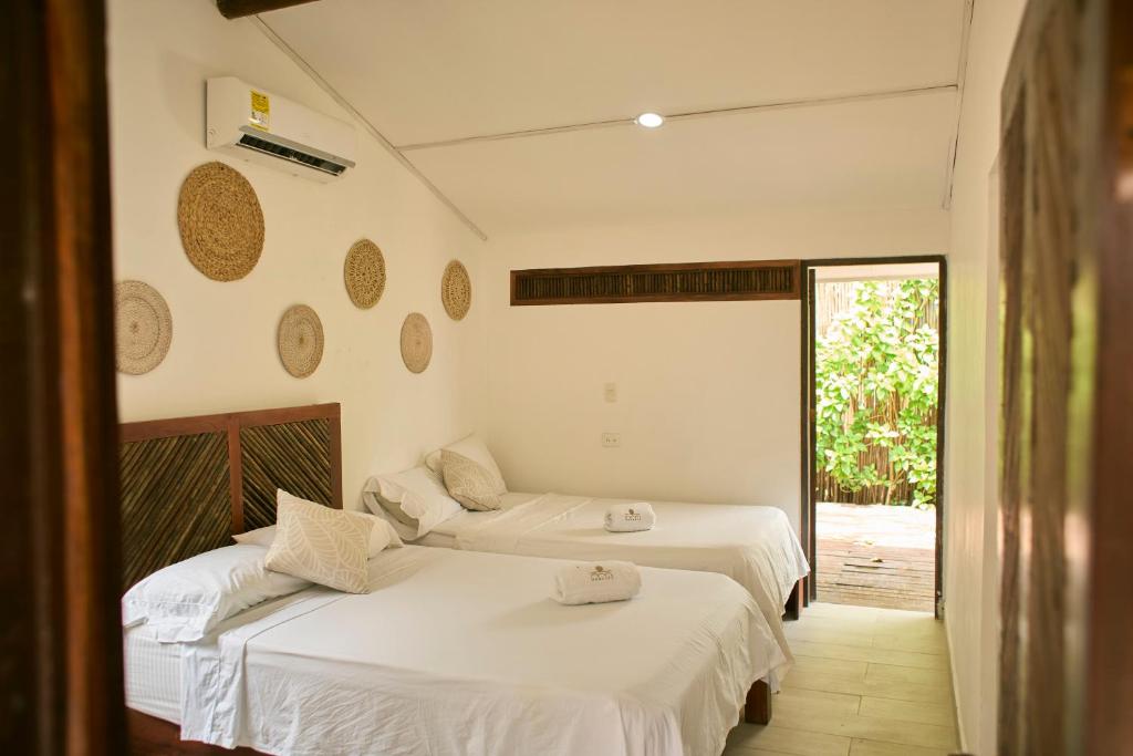 2 Betten in einem Zimmer mit weißen Wänden in der Unterkunft Mangata Beach in Cartagena de Indias