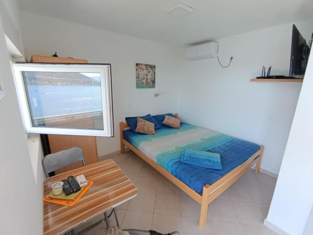Bett in einem Zimmer mit einem Tisch und einem Fenster in der Unterkunft Apartments Eftimov in Tivat