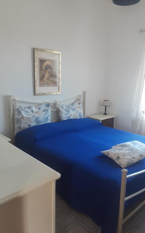 un letto blu in una stanza bianca con un tavolo di Villa Diana a Capoliveri