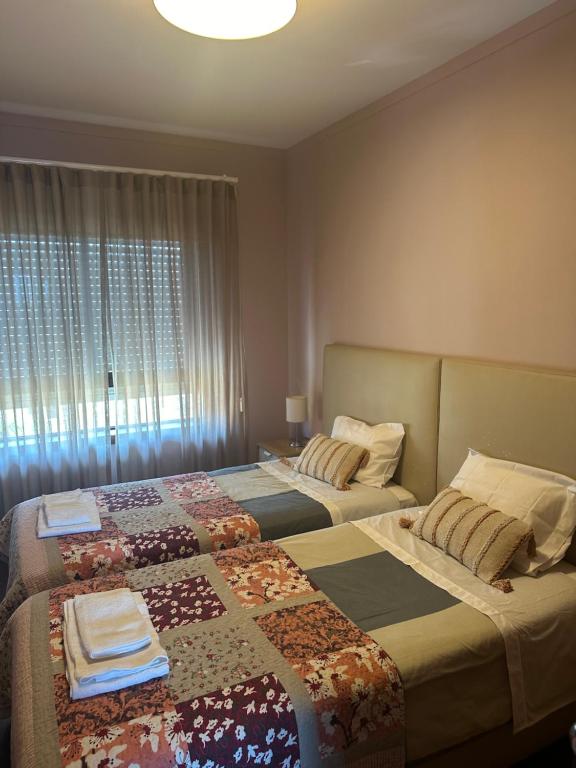 um quarto com 2 camas e uma janela em aerOPOrto Guesthouse em Maia