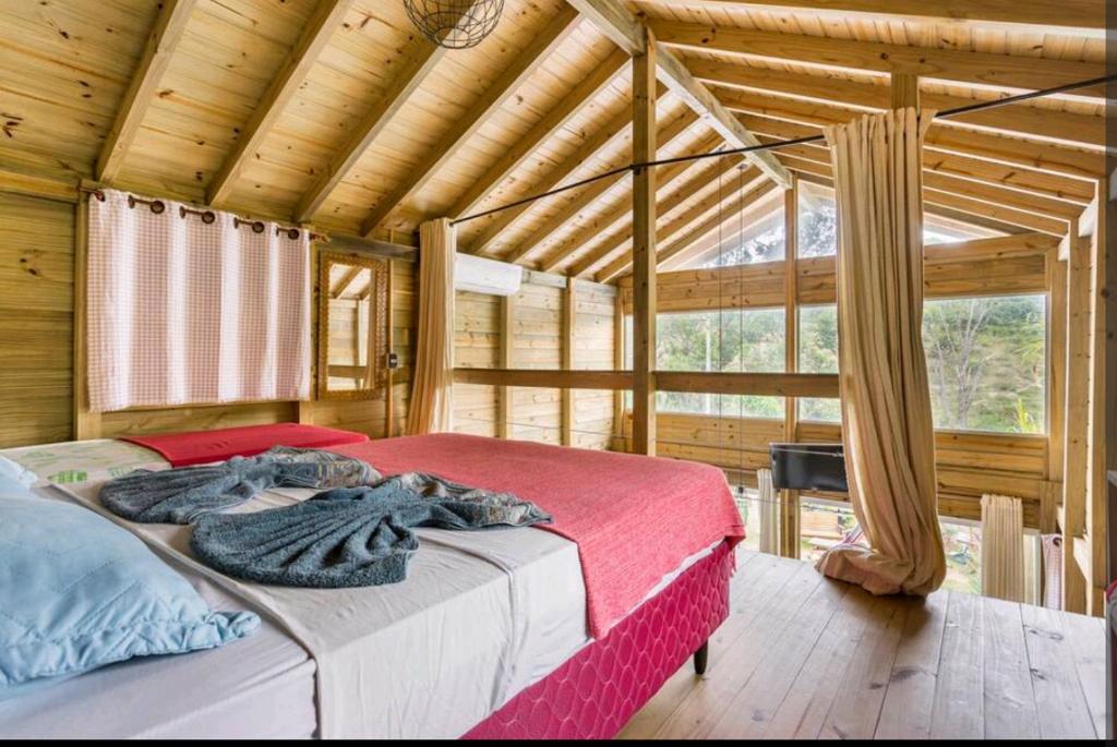 een slaapkamer met een groot bed in een houten kamer bij Sonhos do Rosa pousada in Praia do Rosa