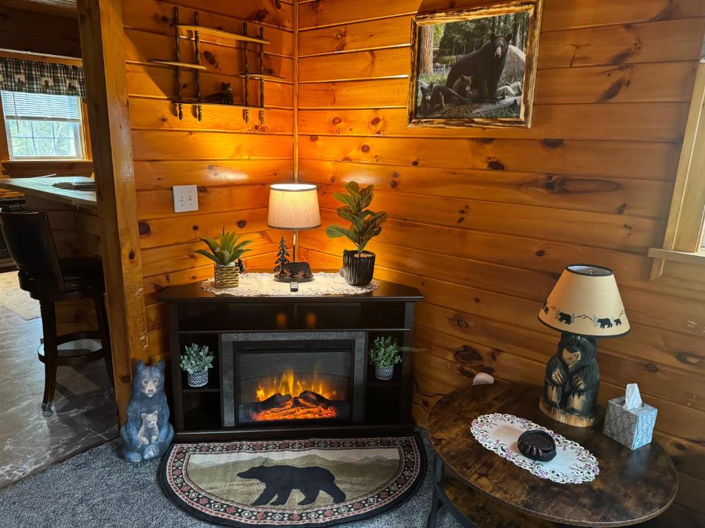 a living room with a fireplace in a log cabin at The Lazy Bear Cabin in Long Lake