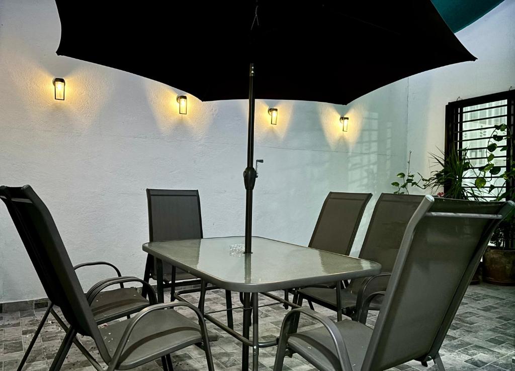 una mesa con sillas y una sombrilla en una habitación en EXCELENTE CASA EN PRIVADA ALBERCA- GYM-JARDÍN- Asador, en Ciudad Valles
