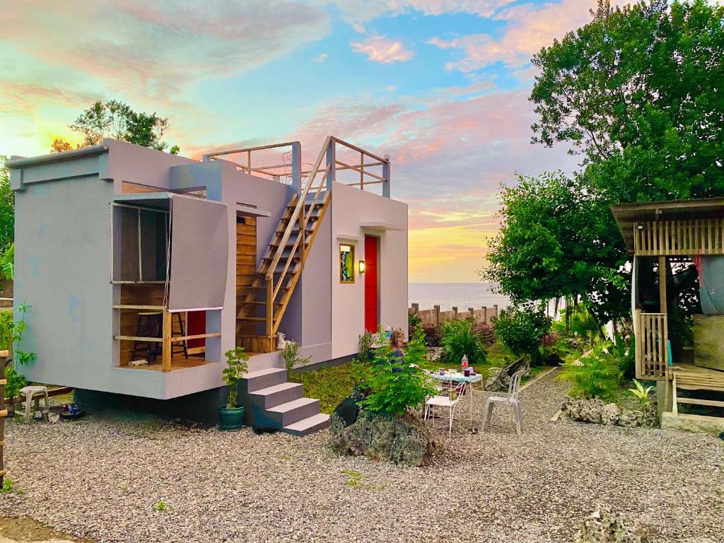 a house with a staircase and a table in the yard at Tiny House's Seafront Room in Camotes Island in Esperanza