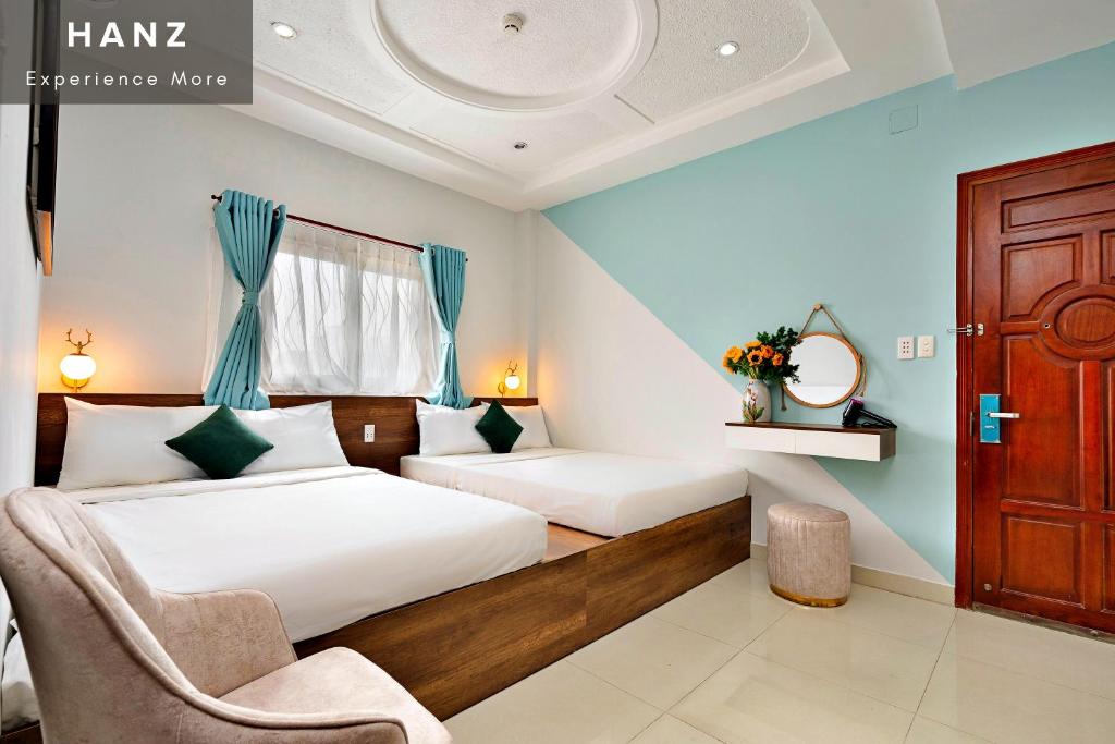 a hotel room with two beds and a chair at HANZ Vivianne Hotel in Ho Chi Minh City
