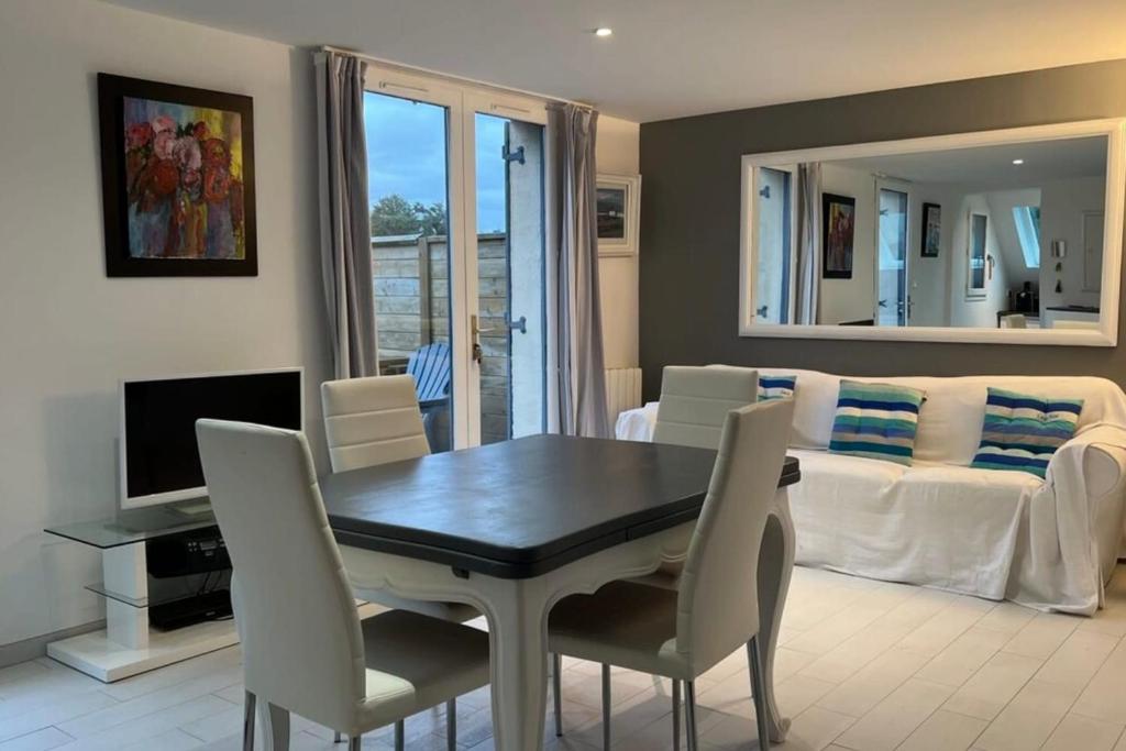 un salon avec une table, des chaises et un canapé dans l'établissement Small cottage for 4 people nestled in the heart of the dunes of Le Touquet, à Le Touquet-Paris-Plage