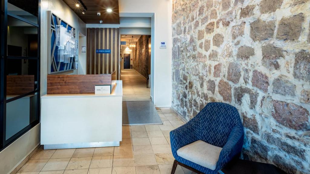 ein blauer Stuhl neben einer Steinmauer in der Unterkunft Holiday Inn Express Morelia Centro Historico in Morelia