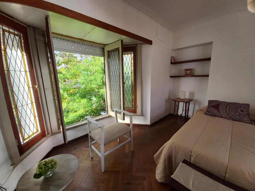a bedroom with a bed and a chair and windows at Casa amplia para 5 personas y cochera, a pasos del centro in La Plata
