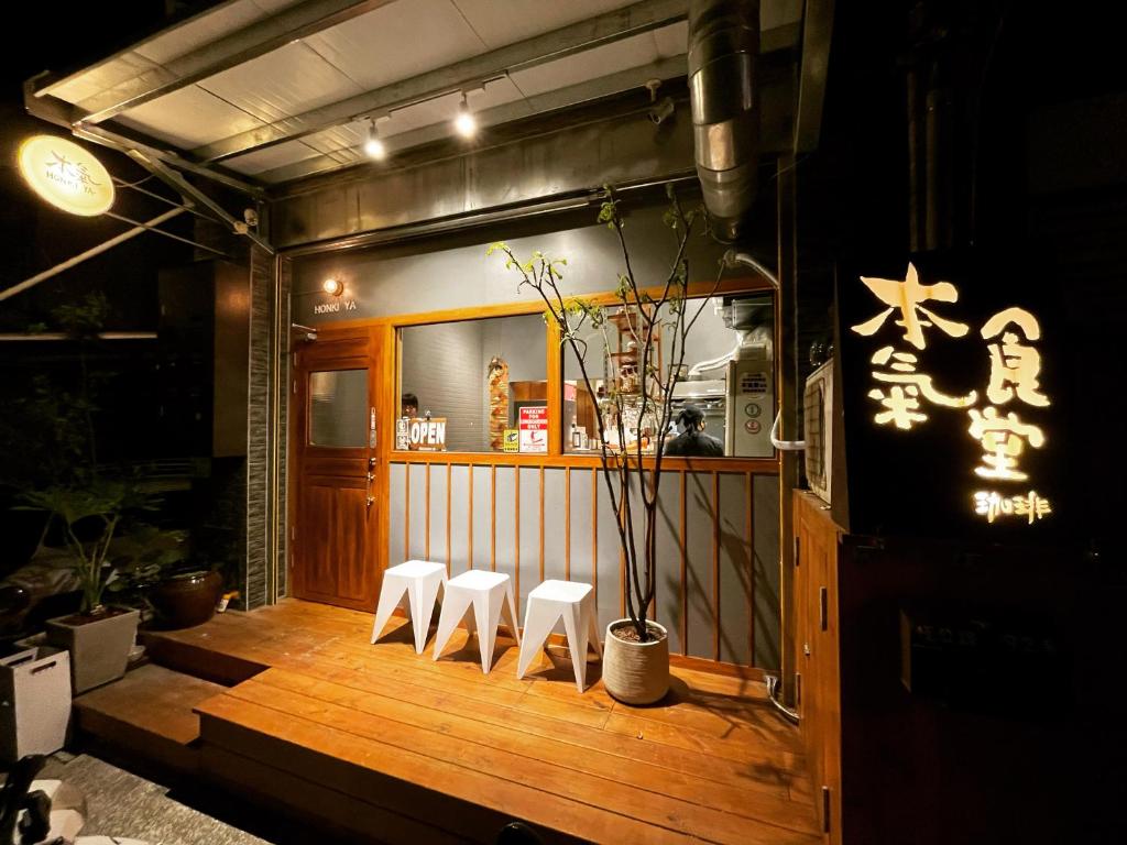 a restaurant with three white stools on a wooden deck at 本氣宿泊Honkiya in Hengchun
