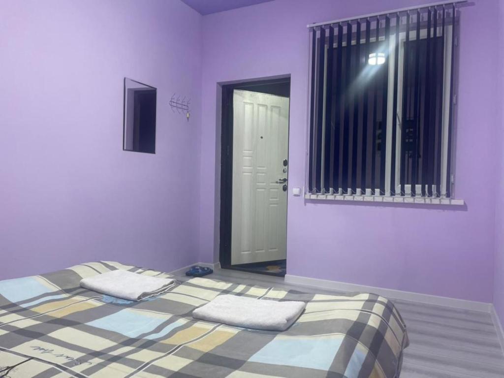 a bedroom with a bed with purple walls and a window at Asian Guest House in Bishkek