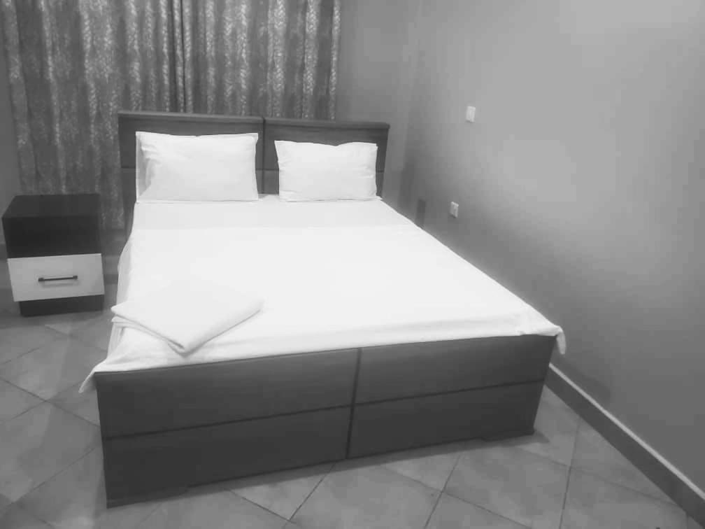 een bed met witte lakens en kussens in een kamer bij Fien in Morogoro