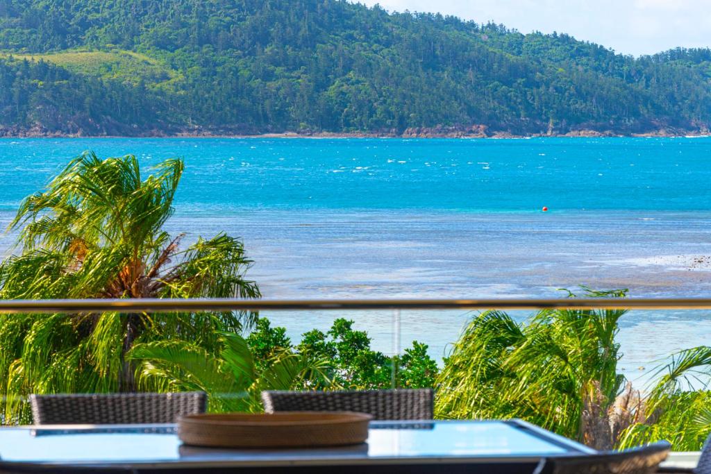 een uitzicht op een strand met een tafel en stoelen bij Beach Lodges in Hamilton Island