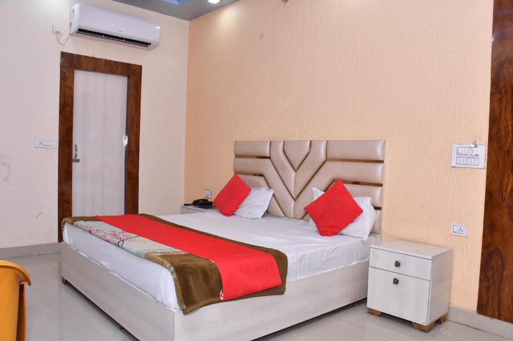 1 dormitorio con 1 cama grande con almohadas rojas en Hotel Adarsh Residency Mangalam Group, en Haridwar